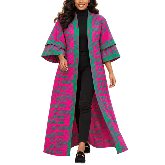 A woman walking outdoors in a long, open-front kaftan-style coat with wide sleeves. The coat has a bold geometric pattern in bright pink and green.
