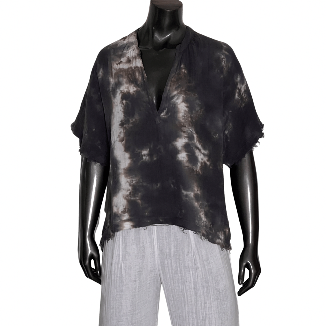 Mannequin wearing a black and gray tie-dye top with white pants on a white background