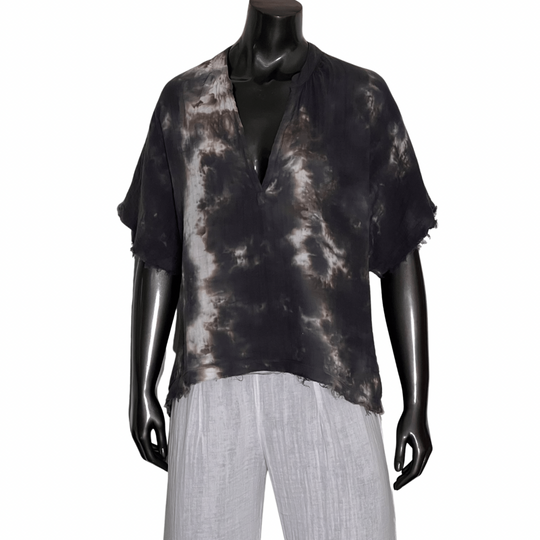 Mannequin wearing a black and gray tie-dye top with white pants on a white background
