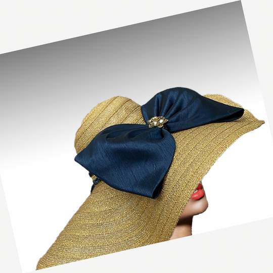 Gold straw hat with a large navy blue bow on a white background