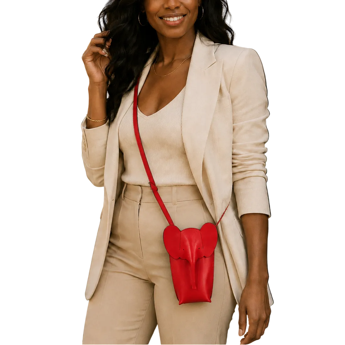 A woman wearing a beige blazer and matching pants carries a small red heart-shaped crossbody bag with a red strap, photographed outdoors in front of a cafe setting.