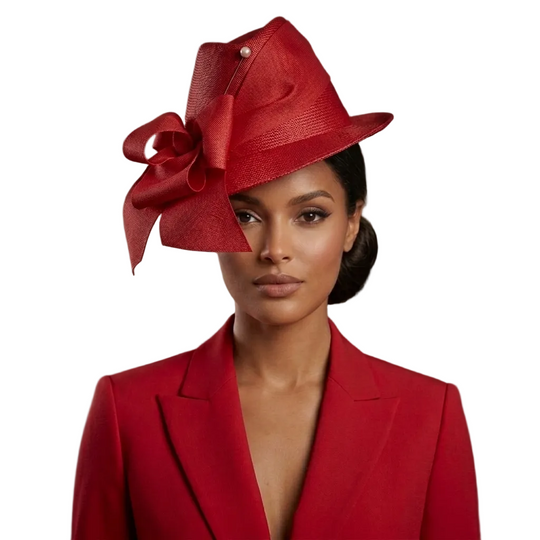 Woman wearing a red hat with a large bow, standing against a neutral background.