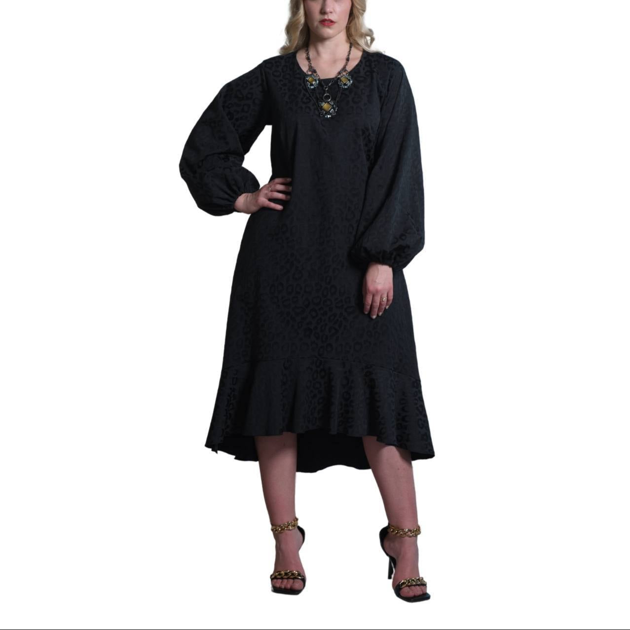 A woman standing in front of a classical columned background, wearing a long black dress with three-quarter sleeves and a V-neck.