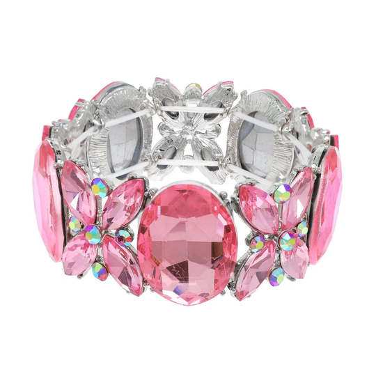 A wide silver-tone cuff bracelet featuring large pink marquise and oval rhinestones, smaller pink floral clusters with iridescent accents, and a central pink oval stone, shown on a plain white background.