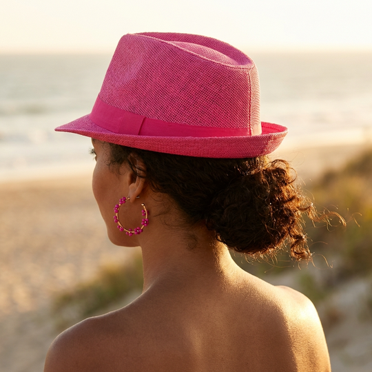 Person wearing a pink hat and earrings with a blurred natural background