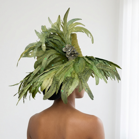 Person wearing a large green feathered headpiece against a white background