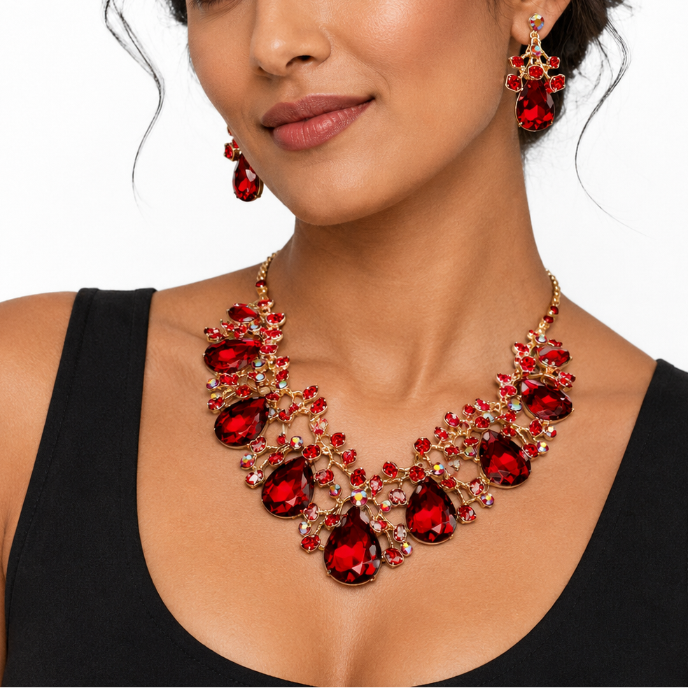 A woman wearing a red and gold statement necklace with matching drop earrings, styled with a black tank top against a plain white background.