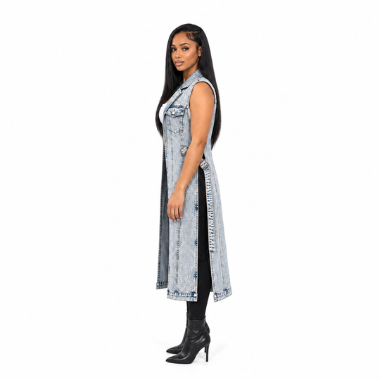 A woman modeling a long sleeveless light-wash denim vest with a front zipper and side slits, paired with black leggings and black high-heeled boots, against a plain white background.