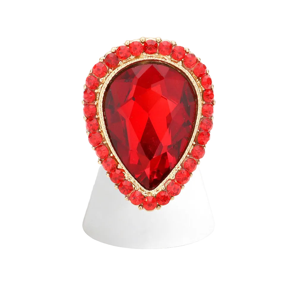 Red teardrop-shaped gemstone ring with gold accents on a white stand
