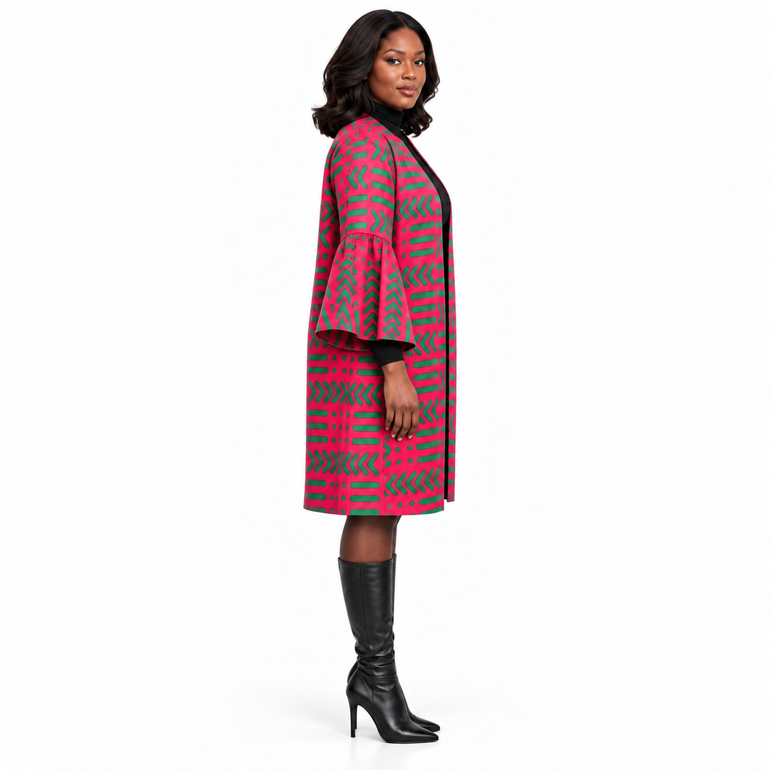 A woman modeling a pink and gray geometric patterned coat with flared sleeves, paired with black knee-high boots, against a plain white studio background.