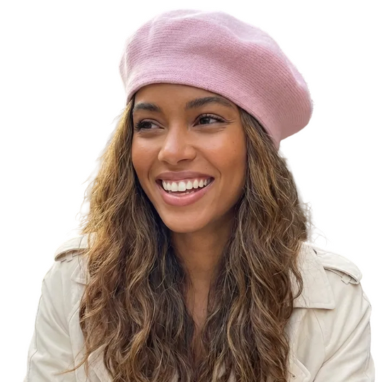 Woman wearing a pink beret and white coat sitting outdoors in a city street.