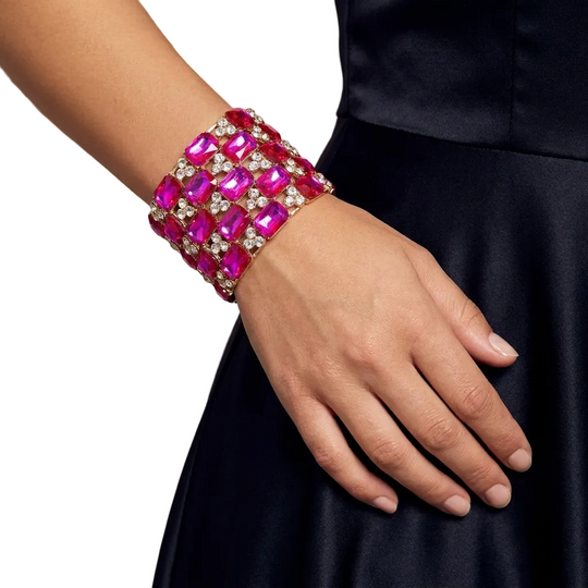 Hand wearing a pink gemstone bracelet with a blurred background