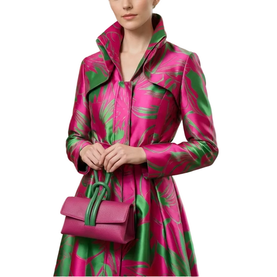 Woman wearing a pink and green patterned coat with a matching handbag in a clothing store.