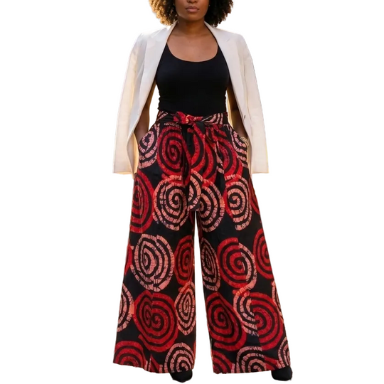 Woman wearing a white blazer, black top, and red patterned pants on a city street.