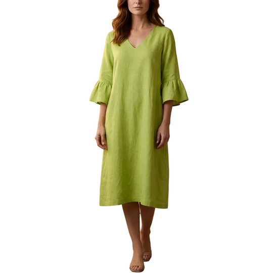 Woman wearing a green dress standing against a beige wall.