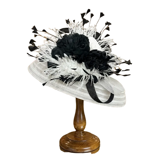 White and black decorative hat on a stand in a store setting with mirrors and shelves.