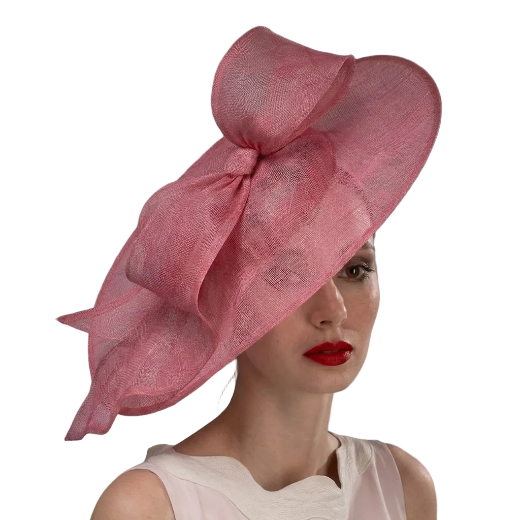 Woman wearing a pink hat with a large bow against a gray background