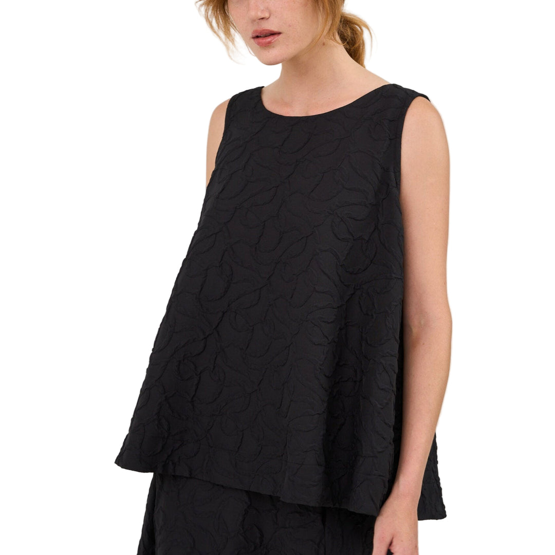 Woman wearing a black sleeveless top and black pants on a white background