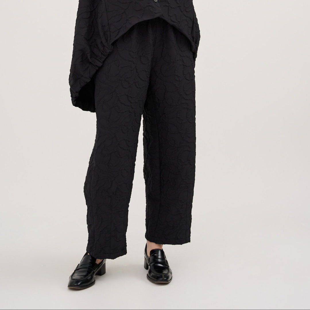 Person wearing a black sleeveless top and pants on a white background