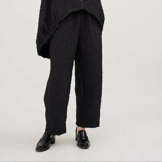 Person wearing a black sleeveless top and pants on a white background