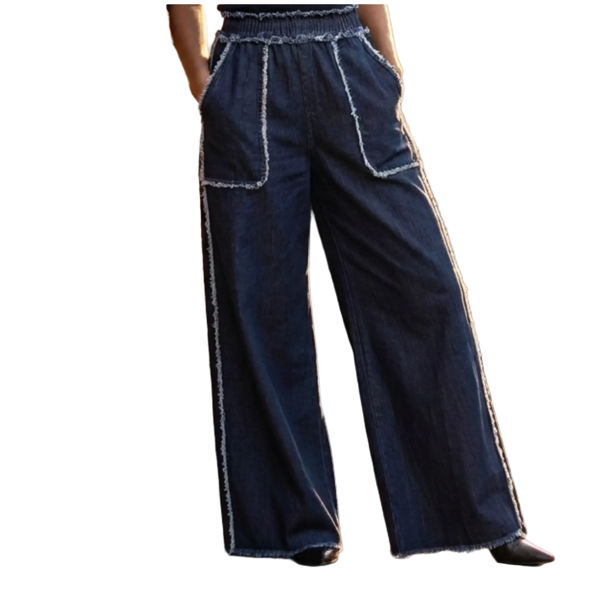 Person wearing blue wide-leg pants with white trim standing against a brick wall.