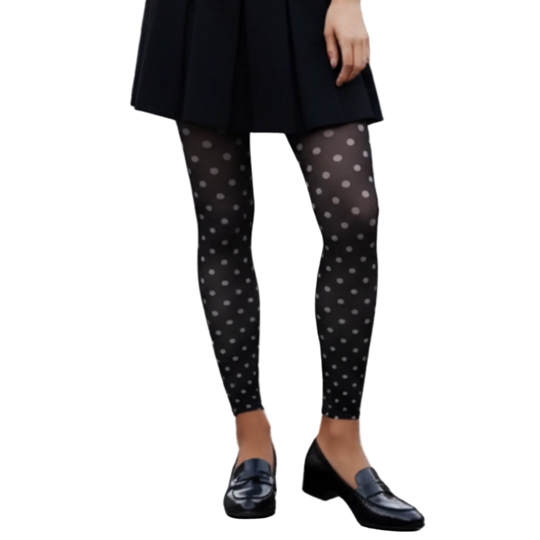 Person wearing black polka dot tights and black shoes on a street.