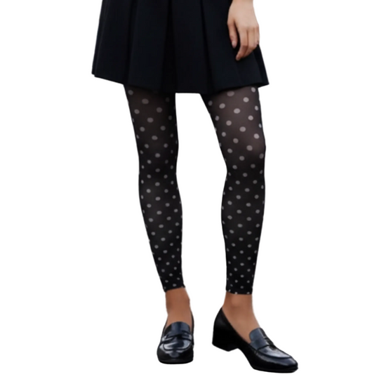 Person wearing black polka dot tights and black shoes on a street.