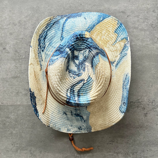 Sun hat with blue and beige marbled pattern on a gray surface