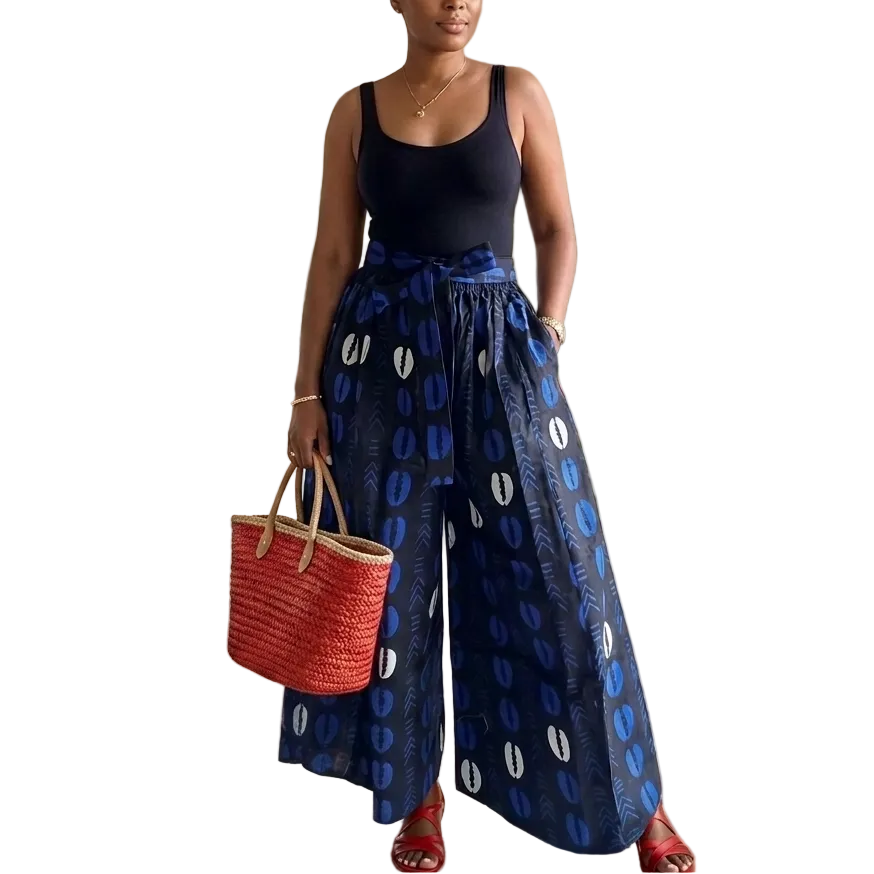 Woman in blue patterned pants and black top holding a red bag in a garden setting