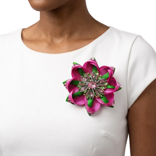 Woman wearing a white top with a pink and green floral brooch.