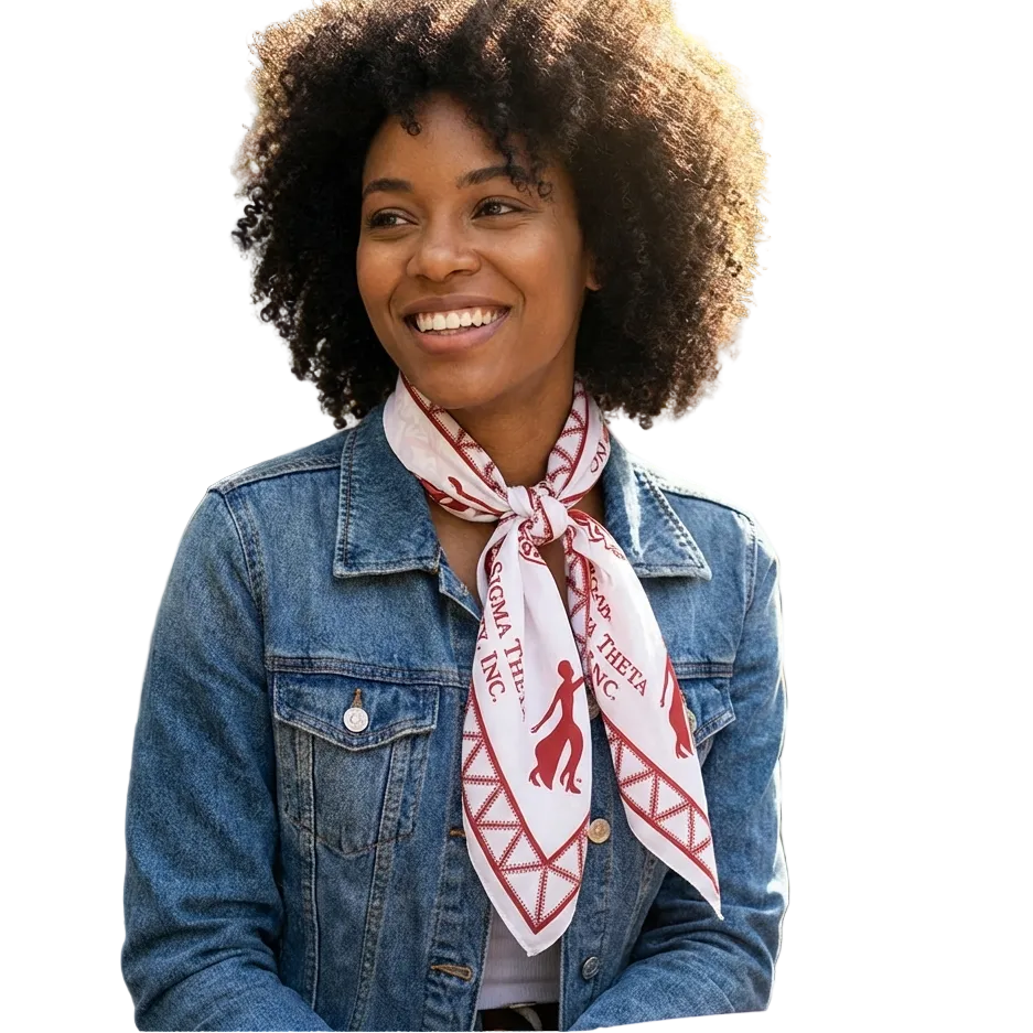 Woman wearing a denim jacket and a scarf with a visible brand logo, sitting outdoors.