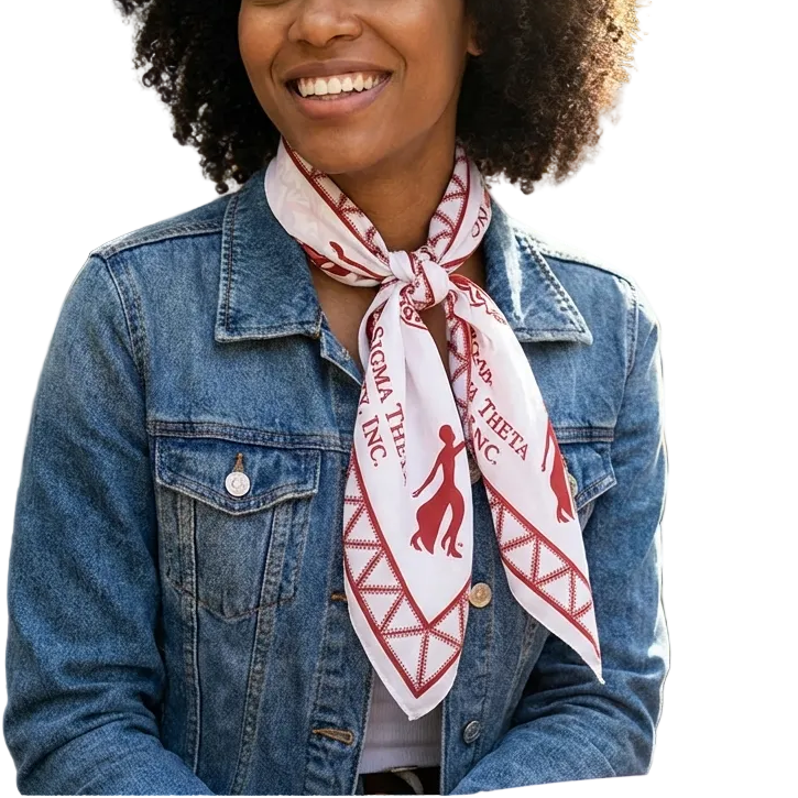Woman wearing a denim jacket and a scarf with a visible brand logo, sitting outdoors.