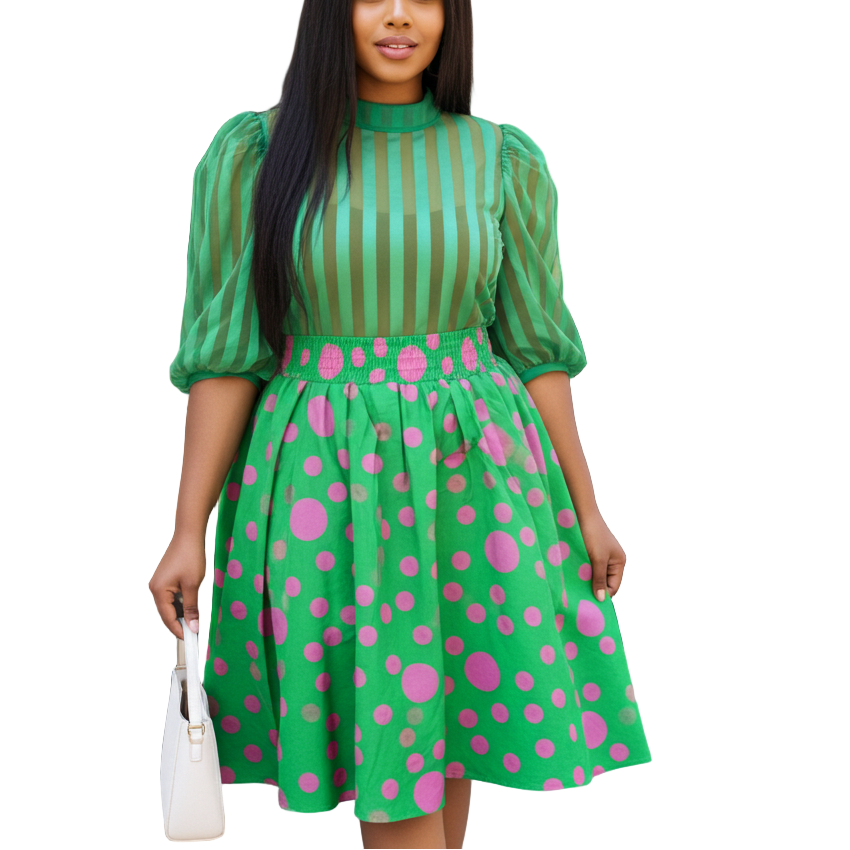 Woman in a green dress with pink polka dots standing in front of a store entrance.
