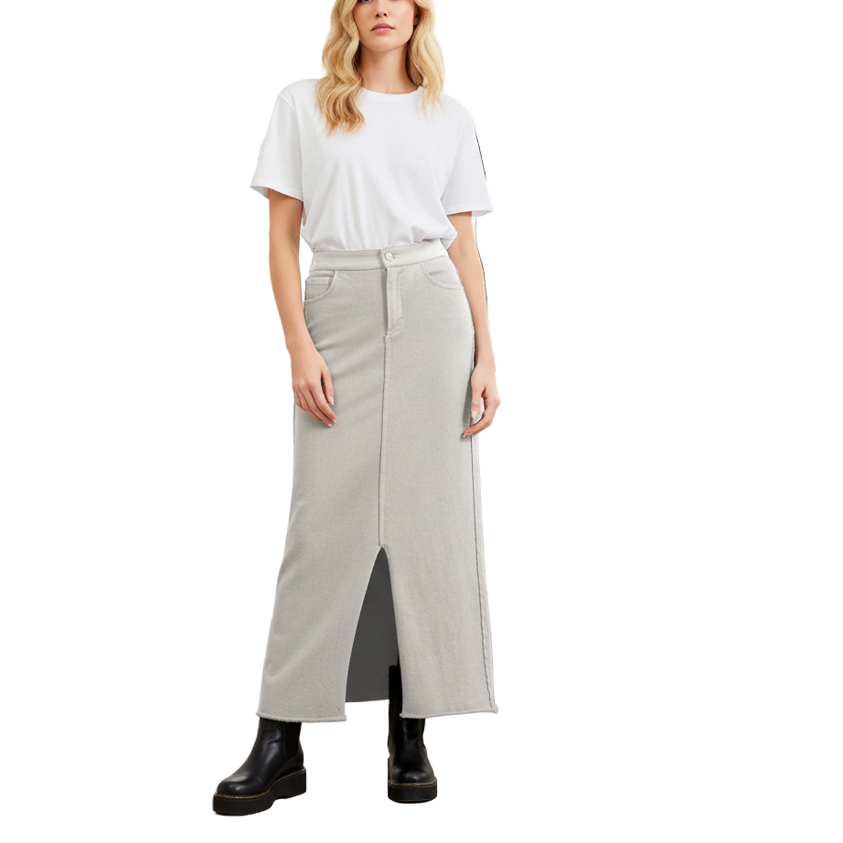 Woman wearing a white t-shirt and light gray skirt standing in a room with large windows.