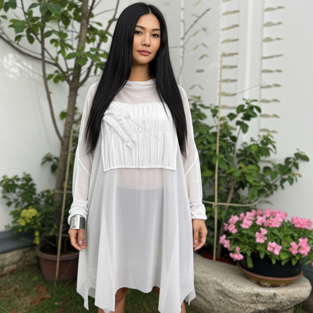 Woman wearing a white dress standing outdoors with plants and flowers in the background