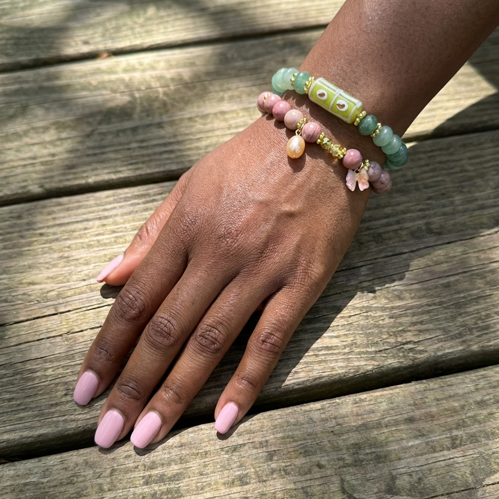 Hand wearing a colorful beaded bracelet on a wooden surface