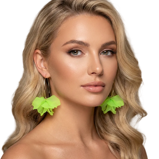 Woman wearing bright green floral earrings with a neutral background