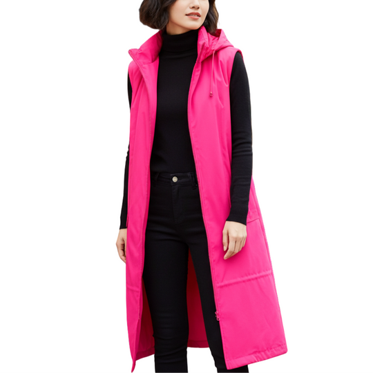 Woman wearing a bright pink vest over a black outfit in front of a bookshelf.