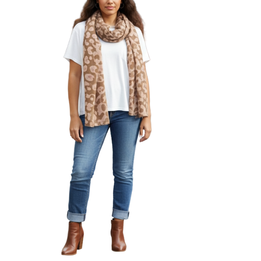 Woman wearing a leopard print scarf, white shirt, blue jeans, and brown boots on a city street.