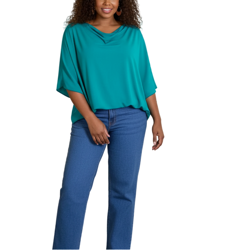 Woman in teal top and blue jeans standing in an art gallery with colorful paintings on the wall.