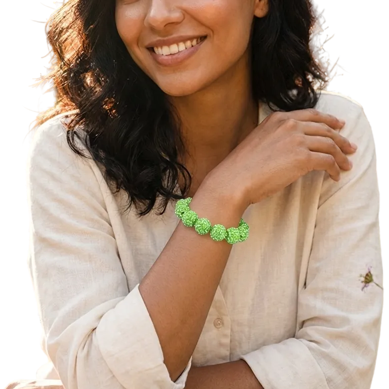 Woman sitting outdoors with a cup of coffee, wearing a green bracelet.