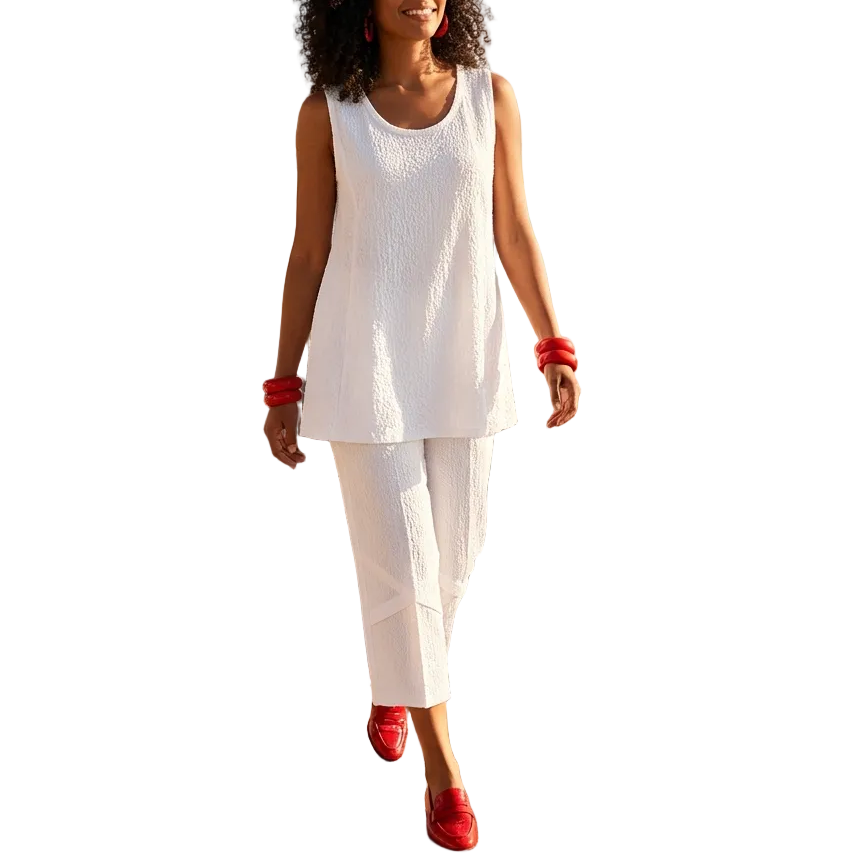 Woman in a white outfit with red shoes walking along a beachside path.
