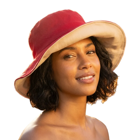 Woman wearing a red and beige bucket hat with a blurred floral background