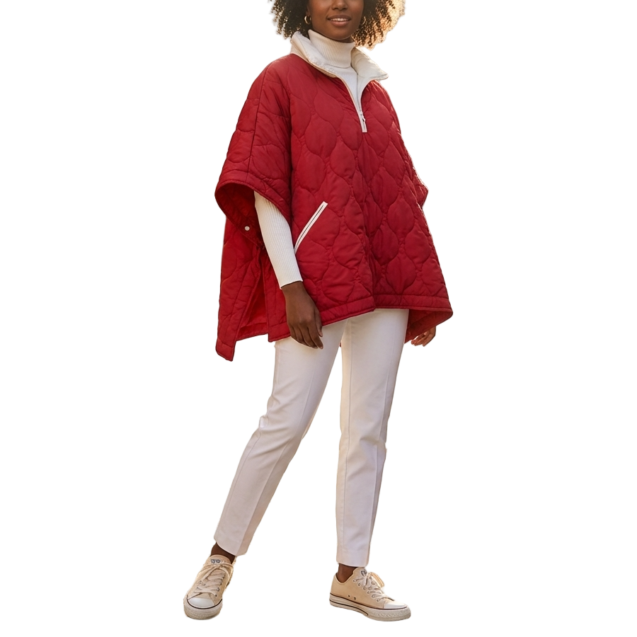 Woman wearing a red puffer coat on a sunlit street with buildings and outdoor seating in the background.