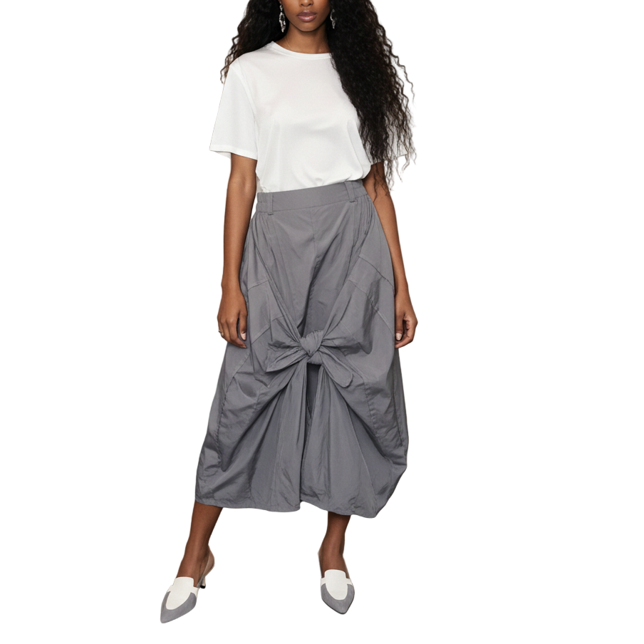 Woman in a white top and gray skirt standing in an art gallery.