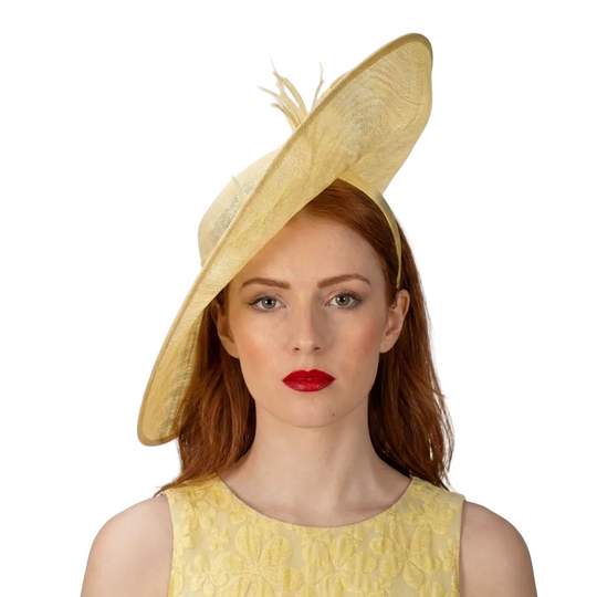 Woman wearing a large yellow hat with a feather against a white background