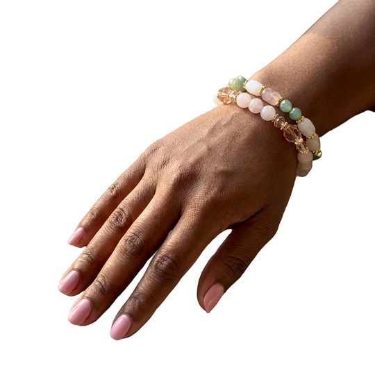 Hand wearing a beaded bracelet on a textured surface