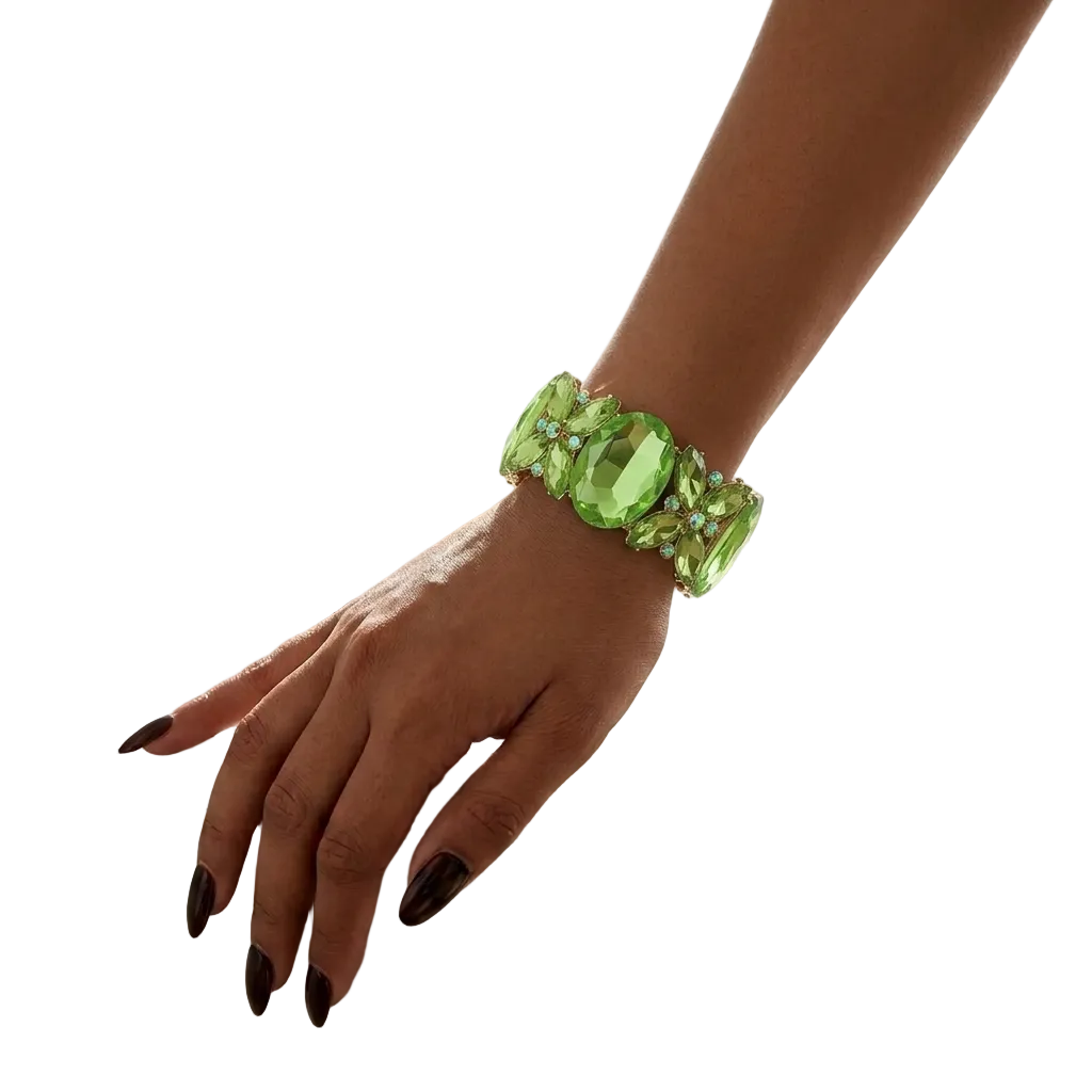 A close-up of a person's hand resting on a white marble vanity table, wearing a chunky green faceted gemstone bracelet.