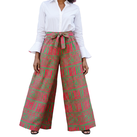 Person wearing a white shirt and red and green patterned pants in front of a colorful mural.