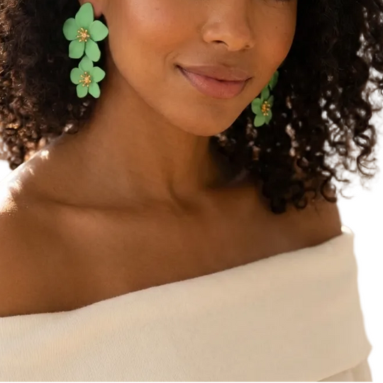 Woman wearing green floral earrings in a softly lit room